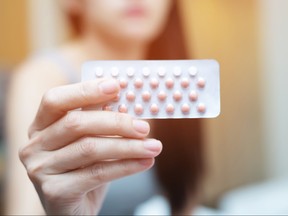 Woman hands opening birth control pills in hand on the bed in the bedroom. Eating Contraceptive Pill.