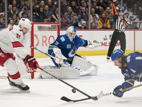 Vancouver Canucks goalie Jacob Markstrom (25)) looks on as Carolina Hurricanes forward Nino Niederreiter (21) battles with Vancouver Canucks defenceman Christopher Tanev (8) in the second period at Rogers Arena.