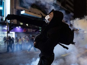 A protester reacts after police fire tear gas to disperse bystanders in a protest in Hong Kong, on Wednesday, Dec. 25, 2019.