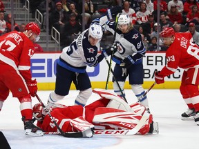 Red Wings goaltender Jonathan Bernier lays on top of the puck after a second period save next to Mark Scheifele (left) and Kyle Connor of the Winnipeg Jets at Little Caesars Arena in Detroit on Thursday. (Getty Images)