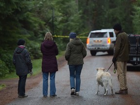 Residents look on as an RCMP vehicle blocks a road near the the scene of a small plane crash on Gabriola Island, B.C., Wednesday, Dec.11, 2019.