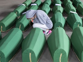 A girl inspects coffins prepared for burial, in Potocari near Srebrenica, Bosnia, Wednesday, July 10, 2019. (AP Photo/Darko Bandic)