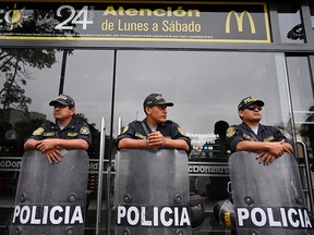 Police stand guard outside a closed McDonald's restaurant, during a protest after the deaths of two teenaged employees, in Lima, Peru December 21, 2019. (REUTERS/Guadalupe Pardo)
