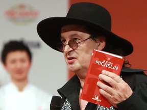 In this file photo taken on Feb. 5, 2018, French chef Marc Veyrat, holds a Michelin guide after being awarded the maximum three Michelin stars, during the Michelin guide award ceremony at La Seine Musicale in Boulogne-Billancourt near Paris.