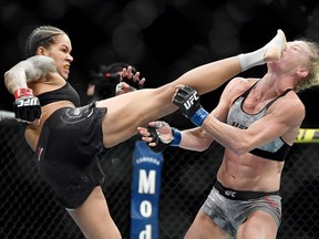 Amanda Nunes (red gloves) lands a kick to the face of Holly Holm (blue gloves) at T-Mobile Arena.