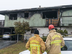 Burnaby, B.C., fire investigators look over the outside a house on the corner of Dundas and Ranelagh Aves., where a person died what officials described as a fast moving fire, Dec., 17, 2019.