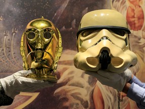 Sotheby's employees hold a "Return of the Jedi" promotional C-3PO Helmet 1983 and a prototype of an Imperial Stormtrooper helmet 1976 created for the first "Star Wars" film during a photocall at Sotheby's in London December 6, 2019. (REUTERS/Thomas Mukoya)