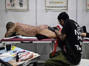 A tattoo artist works on a client during the International Malaysia Tattoo Expo in Kuala Lumpur on November 29, 2019. (MOHD RASFAN/AFP via Getty Images)