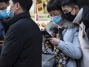 Chinese tourists wearing masks use smartphones in the Ginza shopping district on January 24, 2020 in Tokyo, Japan.