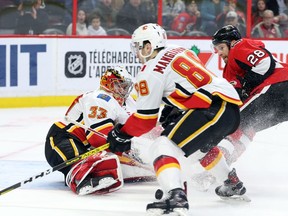 Connor Brown of the Ottawa Senators battles for the puck against goalie David Rittich and Andrew Mangiapane of the Calgary Flames during the third period on Saturday, Jan. 18, 2020.