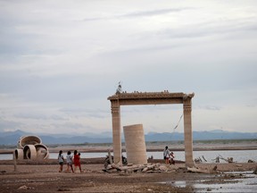 People walk through the ruins of a Buddhist temple, which has resurfaced in a dried-up dam due to drought, in Lopburi, Thailand August 1, 2019. (REUTERS/Soe Zeya Tun/File Photo)