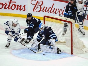Jets goalie Laurent Brossoit (30) makes a save on a shot by Maple Leafs forward Auston Mathews (34) during the third period at Bell MTS Place on Thursday.