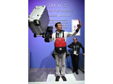 An attendee takes a selfie as he lifts a 50-lb. (22.7-kg) suitcase with the help of the Sarcos Guardian XO exoskeleton arm, Jan. 8, 2020 at the 2020 Consumer Electronics Show (CES) in Las Vegas.