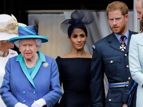 In this file photo taken on July 10, 2018 (L-R) Queen Elizabeth, Meghan, Duchess of Sussex, and Prince Harry, Duke of Sussex come onto the balcony of Buckingham Palace to watch a military fly-past to mark the centenary of the Royal Air Force (RAF).  (Photo by TOLGA AKMEN/AFP via Getty Images)