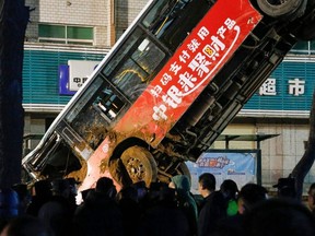 This photo taken on January 13, 2020 shows Chinese rescuers watching as a car is lifted out after a road collapse in Xining in China's northwestern Qinghai province.