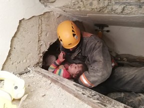 A handout picture taken and released on January 26, 2020 by the Ankara Metropolitan Municipality press office shows a rescue officer with a 2.5-year-old (Nusra) being rescued under the rubble of a building that collapsed in Elazig following January 24's earthquake.