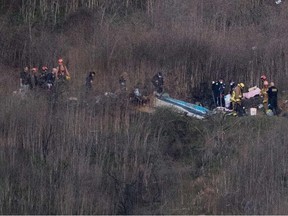 Los Angeles County Fire Department firefighters and coroner staff recover the bodies from the scene of a helicopter crash in Calabasas on January 26, 2020.