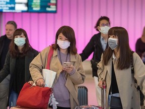 In this file photo taken on January 22, 2020 passengers wear protective masks to protect against the spread of the Coronavirus as they arrive at the Los Angeles International Airport, California.