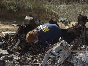 This still image taken from a Jan. 27, 2020, video released by the National Transportation Safety Board (NTSB), shows a NTSB official inspecting the remains of a helicopter which crashed near Calabasa, Calif., on Jan. 26, 2020, killing retired NBA star Kobe Bryant, his daughter, Gianna, and seven others.