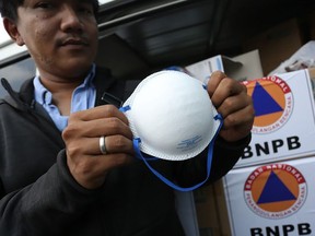 This handout photograph taken and released on January 29, 2020 by the Indonesian National Board for Disaster Management (BNPB) shows an Indonesian official posing with a protective face mask in Jakarta, where a shipment of some 10,000 masks will be sent to Indonesians living in China following the spread of a deadly virus.