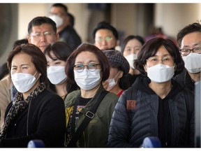 Passengers wear face masks to protect against the spread of the Coronavirus as they arrive on a flight from Asia at Los Angeles International Airport, California, on January 29, 2020.