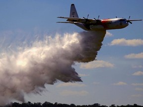 A television reporter stands in front of a Large Air Tanker (LAT) C-130 Hercules as it drops a load of around 15,000 litres during a display by the Rural Fire Service ahead of the bushfire season at RAAF Base Richmond  Sydney, Australia, September 1, 2017.