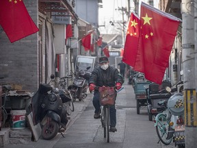 A Chinese man wears a protective mask as he rides his bike in an alley on Jan. 31, 2020, in Beijing, China.