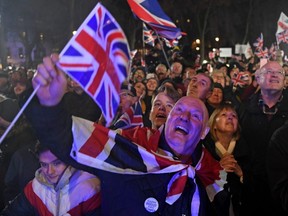 Brexit supporters wave Union flags as they watch the big screen in Parliament Square, venue for the Leave Means Leave Brexit Celebration party in central London on Friday, Jan. 31, 2020, the day that the UK formally leaves the European Union.