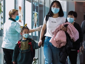 A health officer (left) screens arriving passengers from China at Changi International airport in Singapore on January 22, 2020 as authorities increased measure against coronavirus. (ROSLAN RAHMAN/AFP via Getty Images)