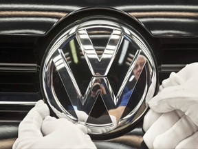 A worker fixes a sign at a Volkswagen Golf car during a press tour in Zwickau, central Germany on Nov. 9, 2012. (THE CANADIAN PRESS/AP, Jens Meyer)