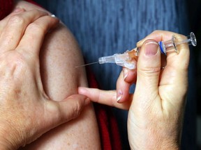 Public health nurse Debbie Abbott injects fellow nurse Robin Leger with influenza vaccine at Hastings Prince Edward Public Health in Belleville, Ont. Tuesday, Dec. 3, 2015.