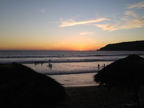 People watch the sun set from the warm waters of the Pacific Ocean in Mazatlan, Mexico.