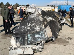 This handout photograph taken and released on January 11, 2019, by the National Security and Defence Council of Ukraine, shows people standing around the remains of the Ukraine International Airlines Boeing 737-800 that crashed outside the Iranian capital Tehran on January 8, 2020. (STR/National Security and Defense Co/AFP via Getty Images)