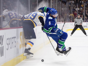 Vancouver Canucks' J.T. Miller, right, loses his footing while vying for the puck against St. Louis Blues' Ivan Barbashev during the first period.