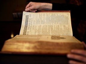 A worker poses with a first edition of the First Folio, the first collected edition of William Shakespeare's works, containing 36 plays, at Christie's auction house in London, Britain April 19, 2016.
