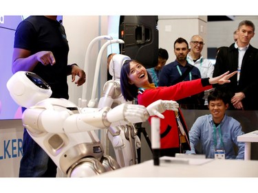 Tanli Yang, a journalist with China Global Television Network, performs yoga poses with Walker, an intelligent humanoid service robot, at the UB Tech booth during the 2020 CES in Las Vegas on Jan. 8, 2020.