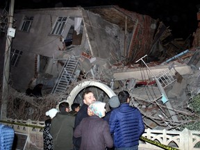 People stand outside a collapsed building after an earthquake in Elazig, Turkey, on Friday, Jan. 24, 2020.