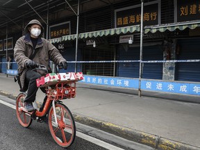 A man wears a mask while riding on mobike past the closed Huanan Seafood Wholesale Market, which has been linked to cases of coronavirus, on Jan. 17, 2020 in Wuhan, Hubei province, China.