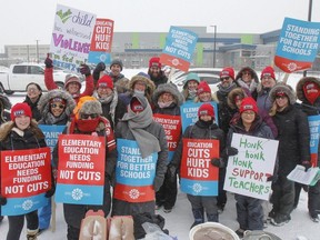 Elementary teachers pose for a group photo in the freezing rain outside Molly Brant Elementary School in Kingston, Ont. on Thursday, Feb. 6, 2020 during the provincewide Elementary Teachers' Federation of Ontario labour strike.