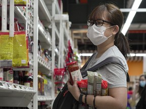 A woman wearing face mask carries a few packets of pasta and bottled sauce at a supermarket after news of the raised outbreak of coronavirus became public people have been panicked to stock up on necessities  as on Feb. 9, 2020 in Singapore. (Ore Huiying/Getty Images)