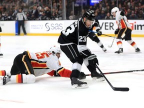 Dustin Brown #23 of the Los Angeles Kings skates with the puck past the defense of Noah Hanifin #55 of the Calgary Flames during the second period of a game at Staples Center on February 12, 2020 in Los Angeles, California.