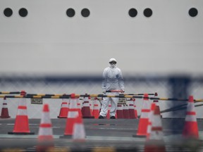 A worker wears a protective suit and a mask as he works in front of the quarantined Diamond Princess cruise ship, docked at the Daikoku Pier on Feb. 20, 2020 in Yokohama, Japan. (Tomohiro Ohsumi/Getty Images)