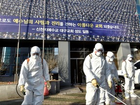 Workers from a disinfection service company sanitize a street in front of a branch of the Shincheonji Church of Jesus the Temple of the Tabernacle of the Testimony where a woman known as "Patient 31" attended a service in Daegu, South Korea, Feb. 19, 2020.