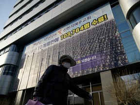 A woman wearing a mask to prevent contracting the coronavirus walks past a branch of the Shincheonji Church of Jesus the Temple of the Tabernacle of the Testimony in Daegu, South Korea Feb. 21, 2020.   REUTERS/Kim Hong-Ji