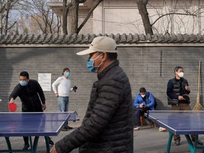 People wearing face masks play table tennis at a park, following an outbreak of the novel coronavirus in the country, in Beijing, Feb. 21, 2020. REUTERS/Stringer