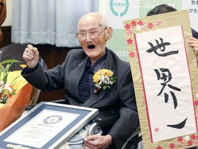 In this Feb. 12, 2020, file photo, Chitetsu Watanabe, 112, poses next to the calligraphy he wrote after being awarded as the world's oldest living male by Guinness World Records, in Joetsu, Niigata prefecture, northern Japan. The Japanese man who received his certificate as the world's oldest man with a raised fist and big smiles earlier this month has died at 112. Guinness World Records confirmed Tuesday, Feb. 25, 2020 he had died Sunday. (Kyodo News via AP, File)