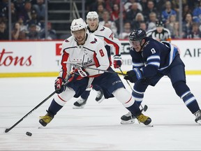 Jets' Andrew Copp (9) attempts to get Capitals' Alex Ovechkin (8) off the puck during second period on Thursday, February 27, 2020. THE CANADIAN PRESS/John Woods