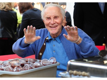 Actor Kirk Douglas displays his hands with food-serving gloves as celebrities turn out to feed the homeless and those less fortunate a lunchtime meal at the Los Angeles Mission on Nov. 23, 2011 in downtown Los Angeles for Thanksgiving.  (AFP PHOTO / Frederic J. BROWN)