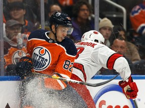 Edmonton Oilers' Caleb Jones (82) battles Carolina Hurricanes' Jordan Martinook (48) at Rogers Place on Dec. 10, 2019.