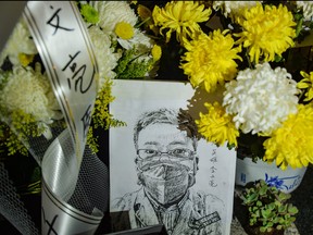 This photo taken on Feb. 7, 2020 shows a photo of the late ophthalmologist Li Wenliang with flower bouquets at the Houhu Branch of Wuhan Central Hospital in Wuhan in China's central Hubei province. (STR/AFP via Getty Images)
